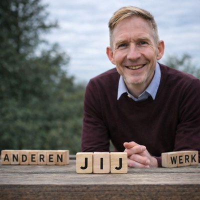 Ron Meijering, NLP- en hypnotherapeut, zittend aan een tafel met houten blokken ‘anderen’, ‘jij’ en ‘werk’, als symbool voor grenzen stellen en zelfliefde.